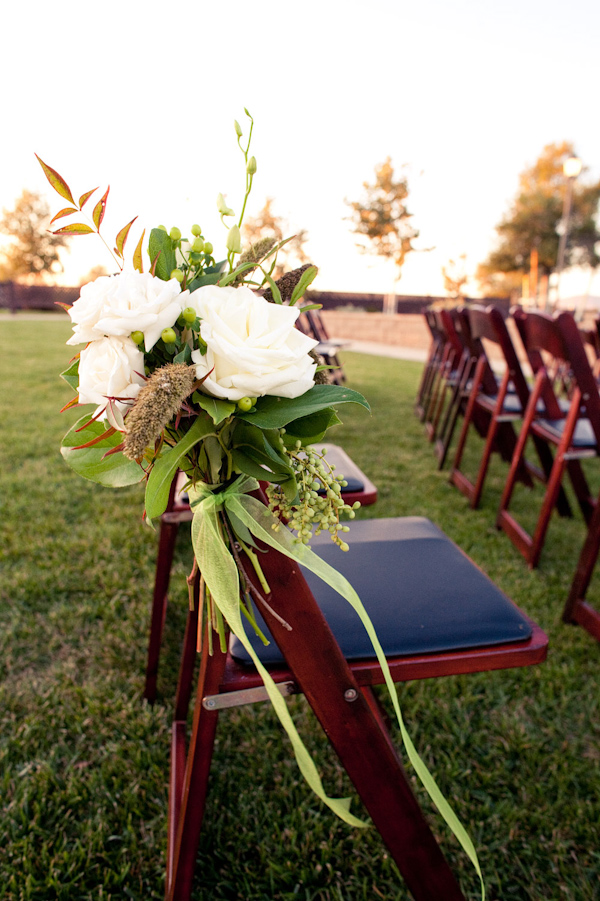 Ceremony seating floral details - White, yellow, and green floral arrangement with dark blue seating pad - photo by Orange County based wedding photographers Mark Brooke